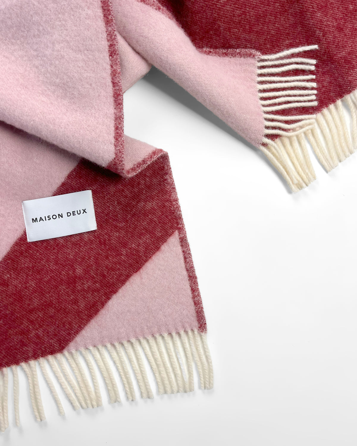 Close-up of pink and bordeaux swirl wool throw with fringe
