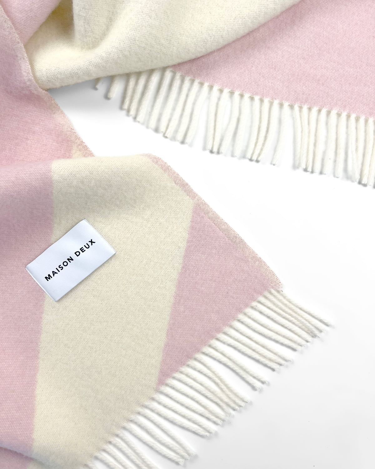 Close-up of pink and butter yellow swirl wool throw with fringe
