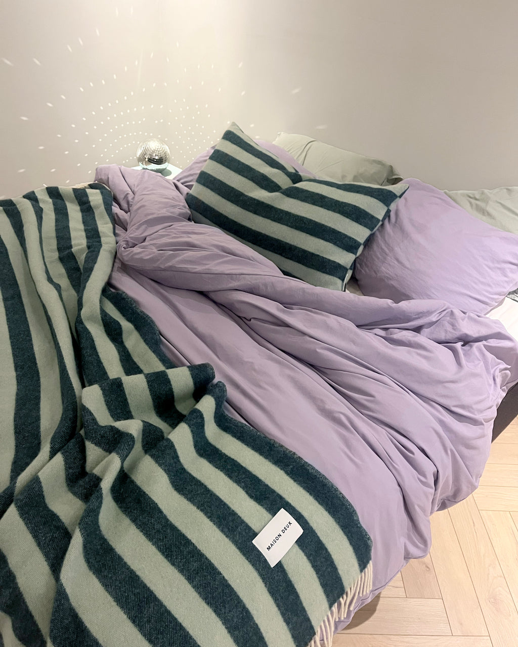Dark green and sage striped wool throw draped over a bed