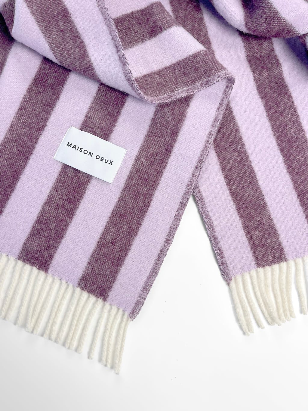 Close-up of lilac and aubergine striped wool throw with fringe
