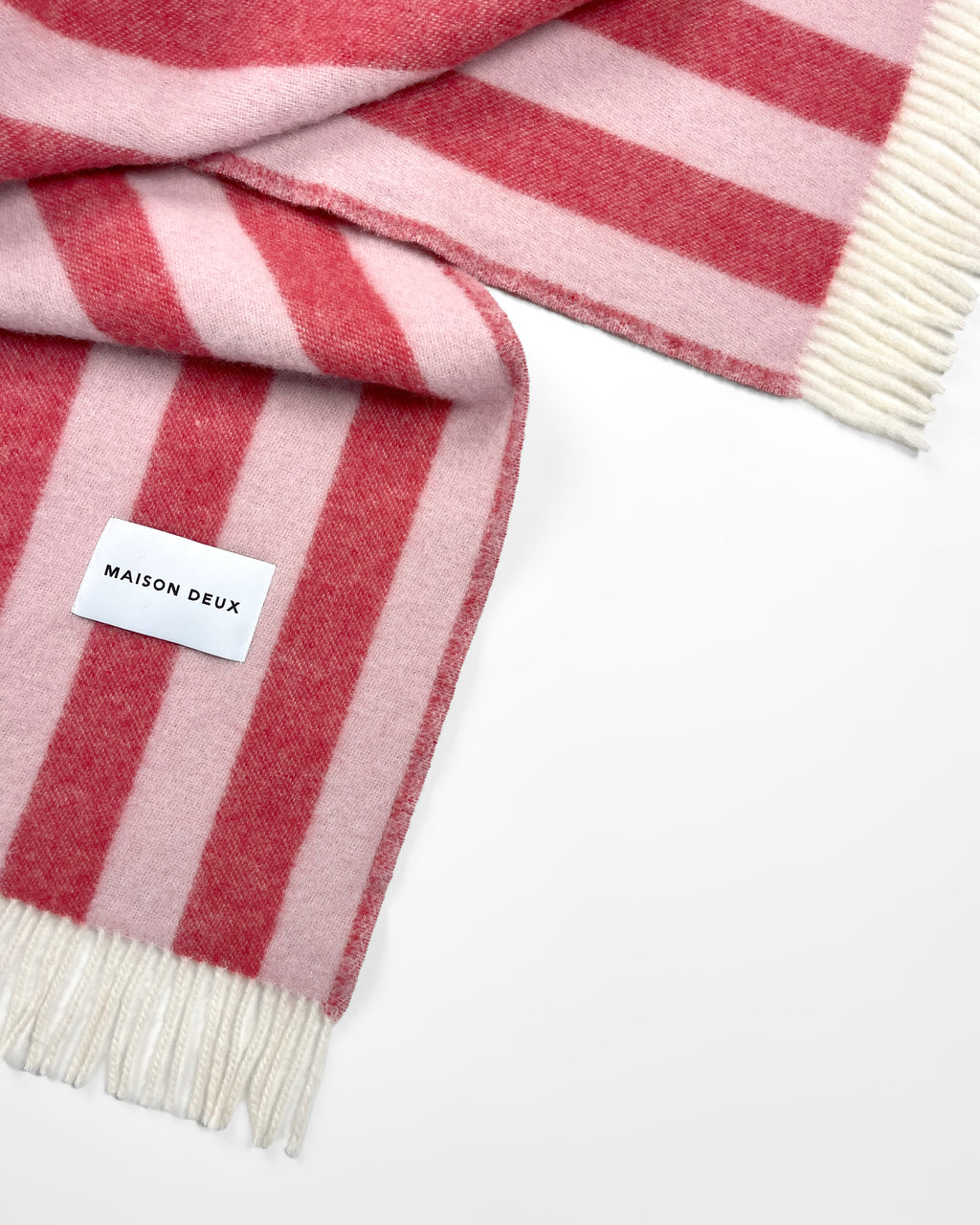 Close-up of pink and cherry red striped wool throw with fringe

