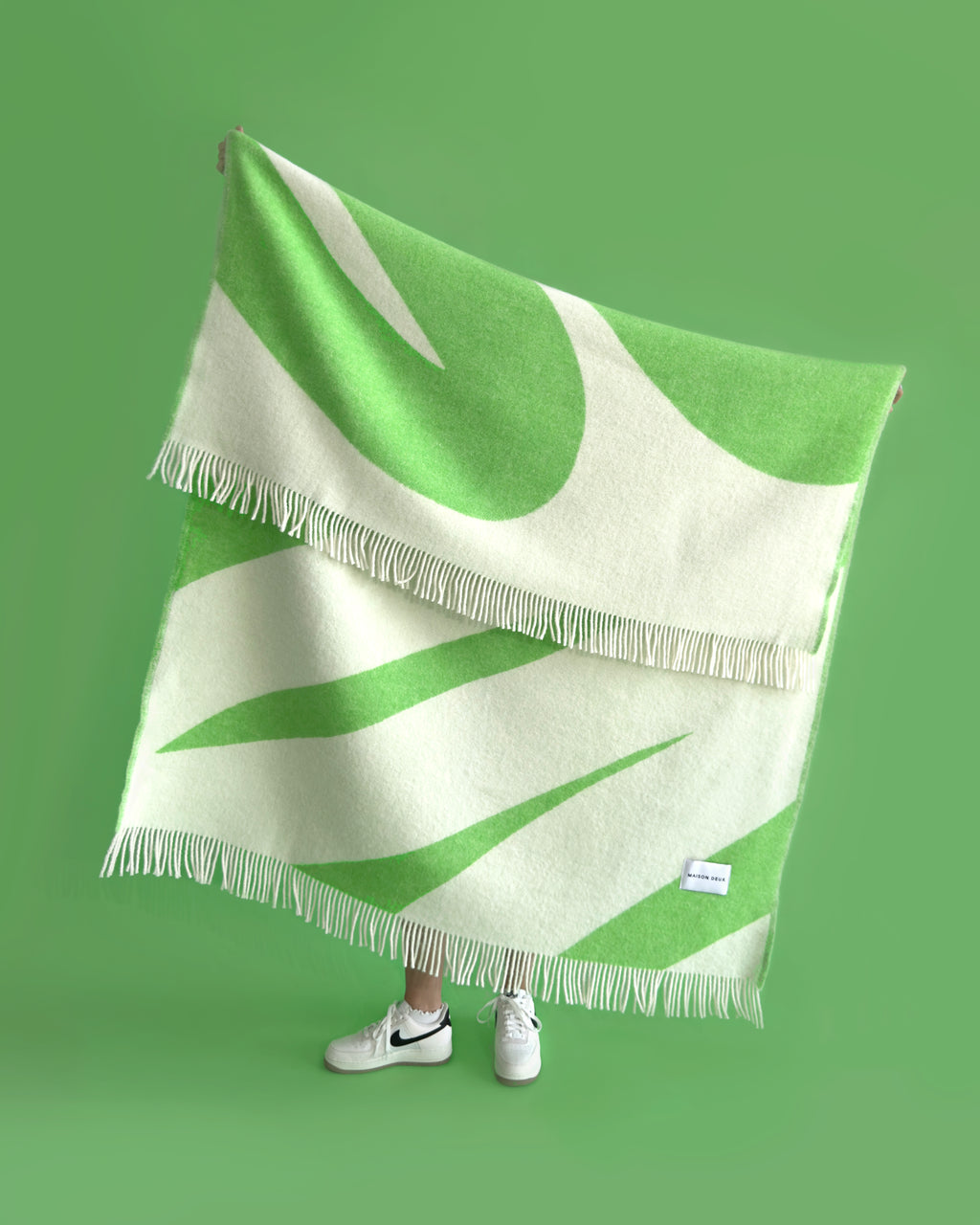 Apple green and white swirl wool plaid hung by a person
