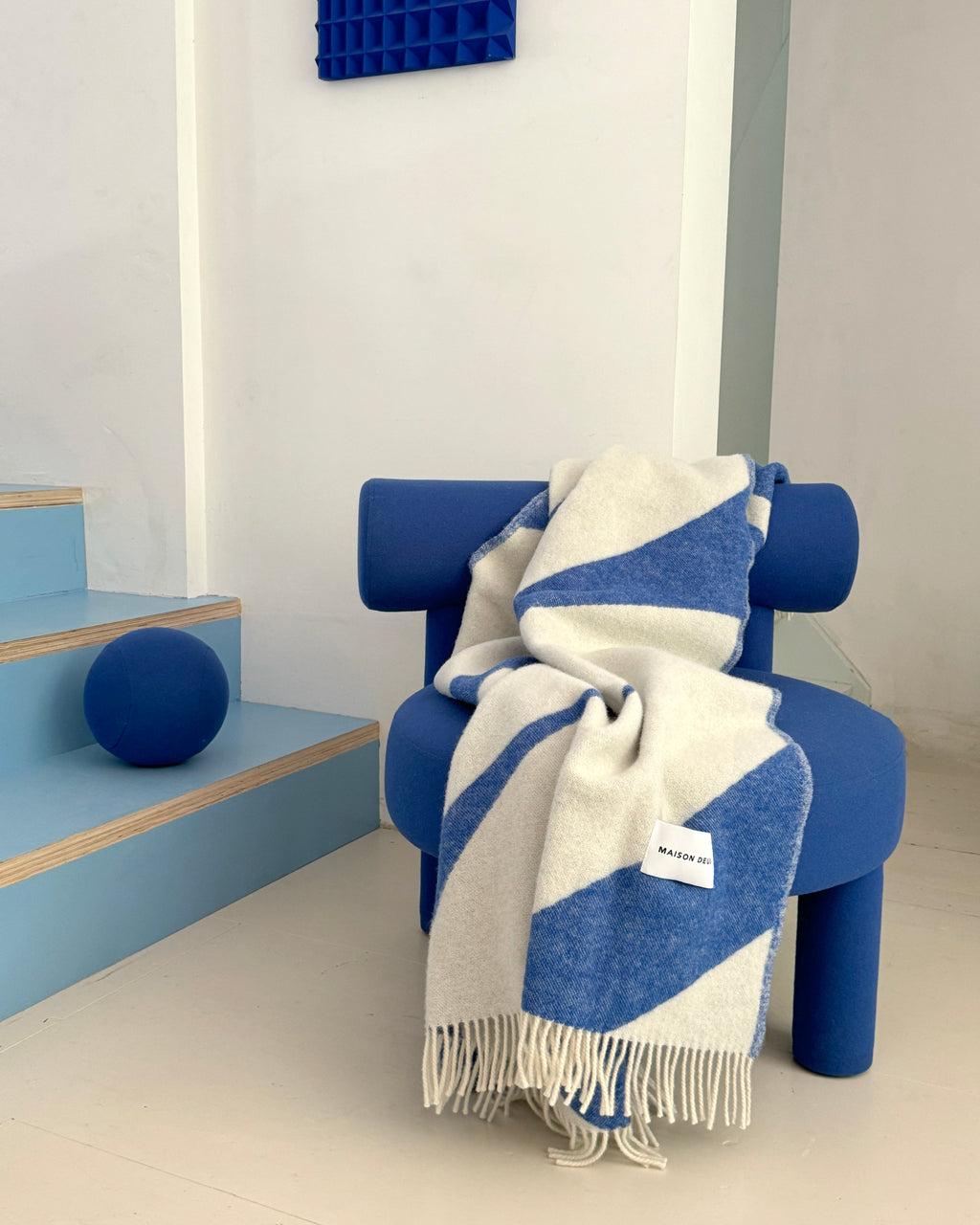 Cobalt blue and white swirl wool plaid draped over chairs in styled room
