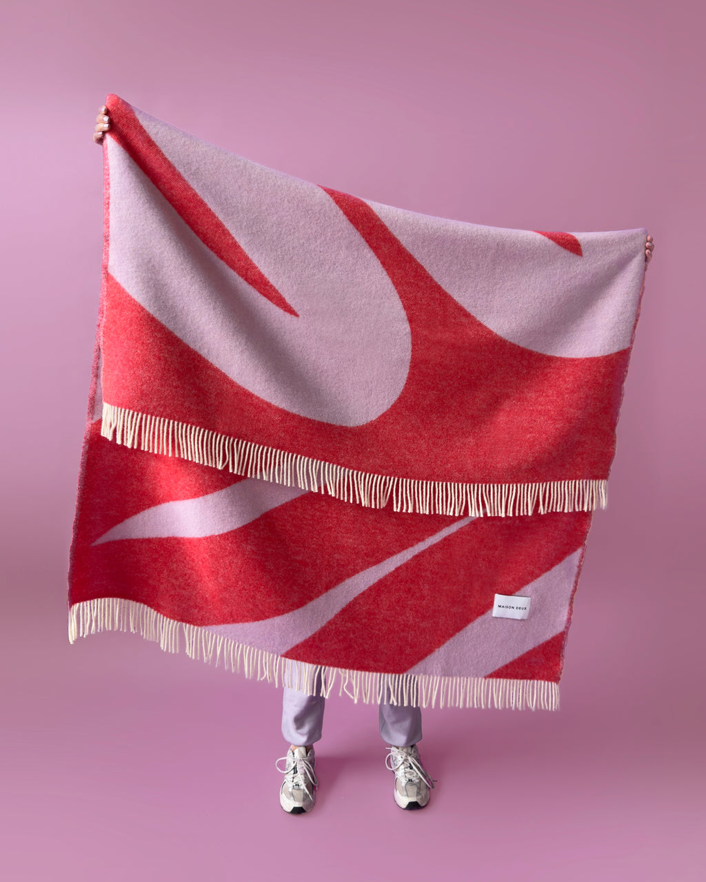 Lilac and scarlet swirl wool plaid hung by a person
