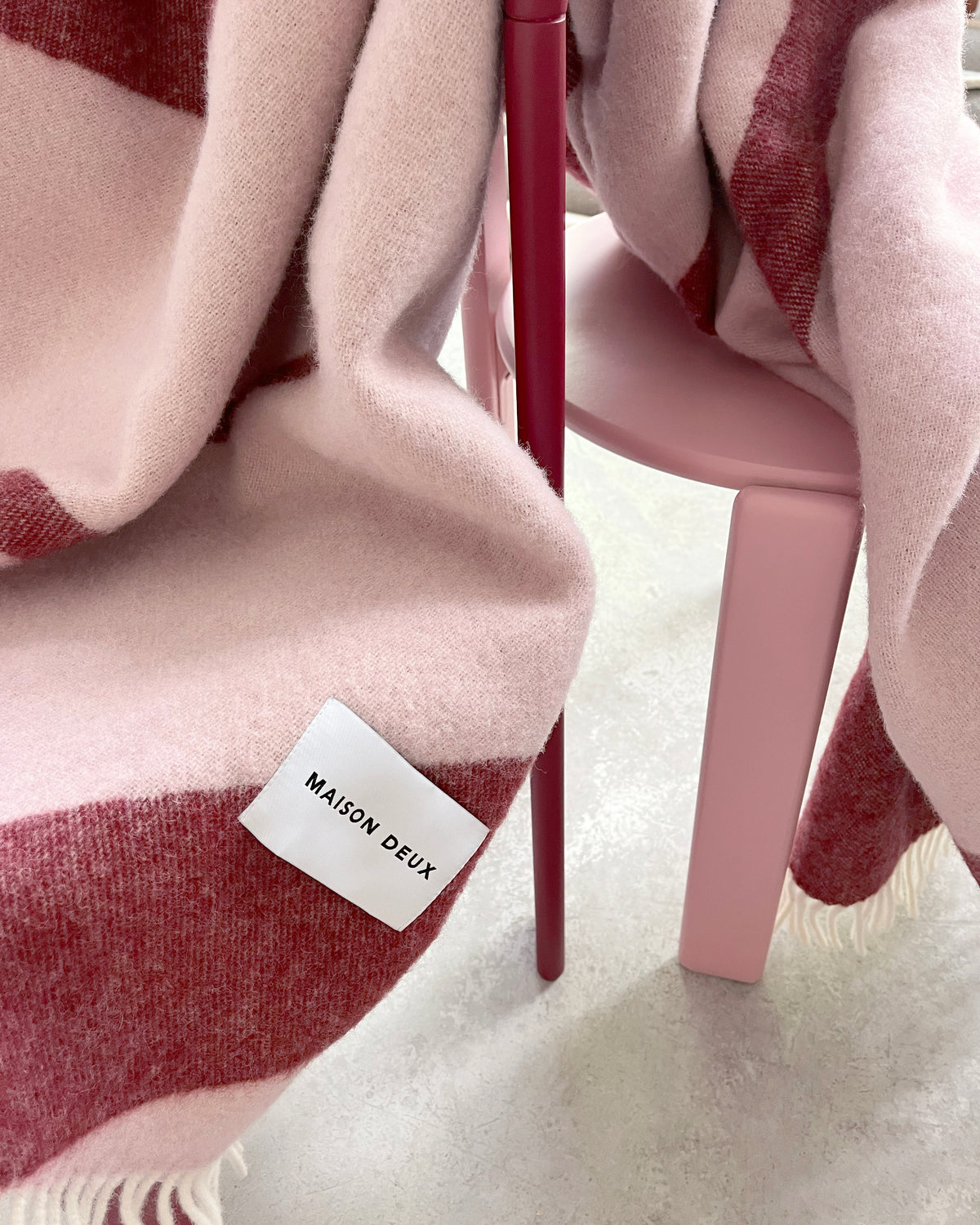 Pink and bordeaux swirl wool plaid draped over chair
