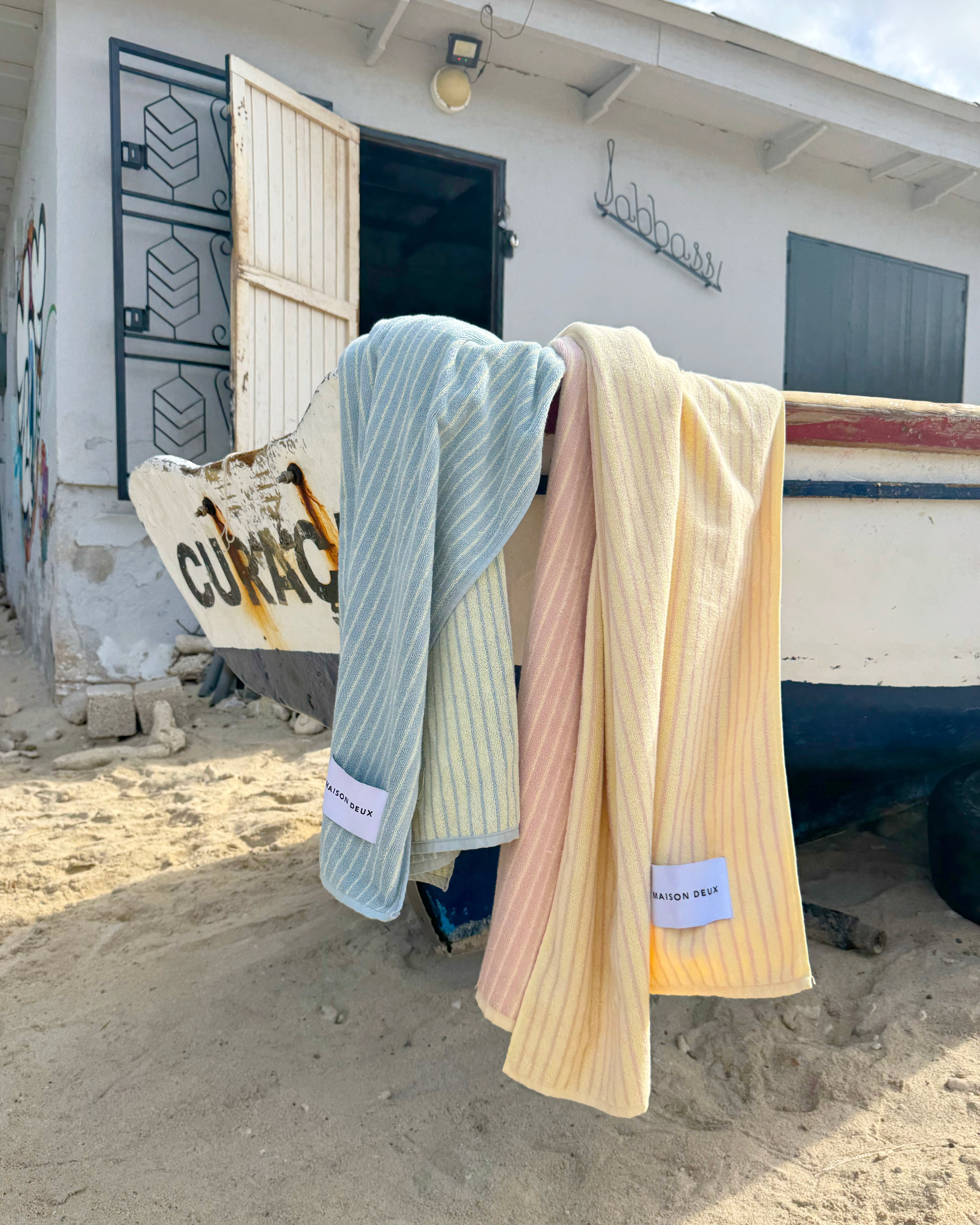 Blue and butter yellow striped beach towel hanging to dry outdoors