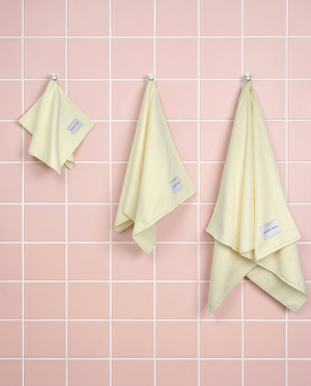 Solid butter yellow organic cotton towels shown in guest, hand and bath sizes