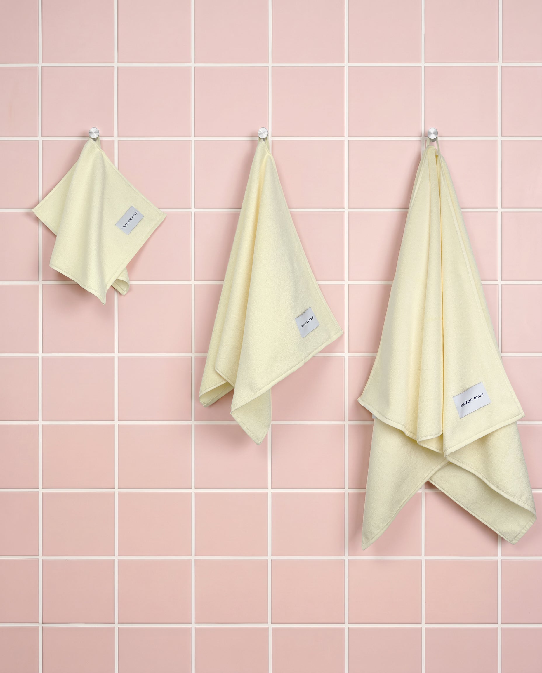 Solid butter yellow organic cotton towels shown in guest, hand and bath sizes