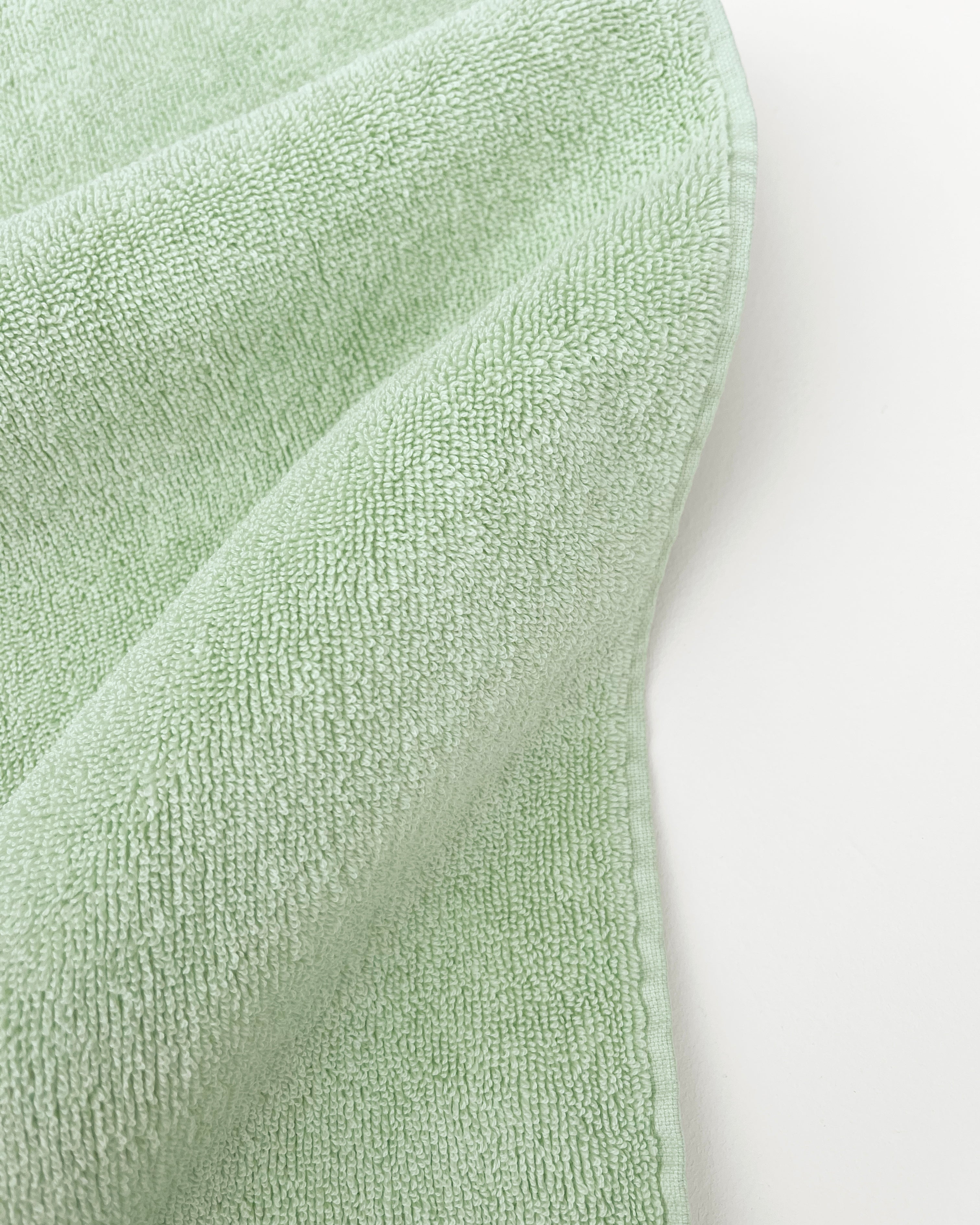 Close-up of dense GOTS-certified organic cotton terry weave, sage green