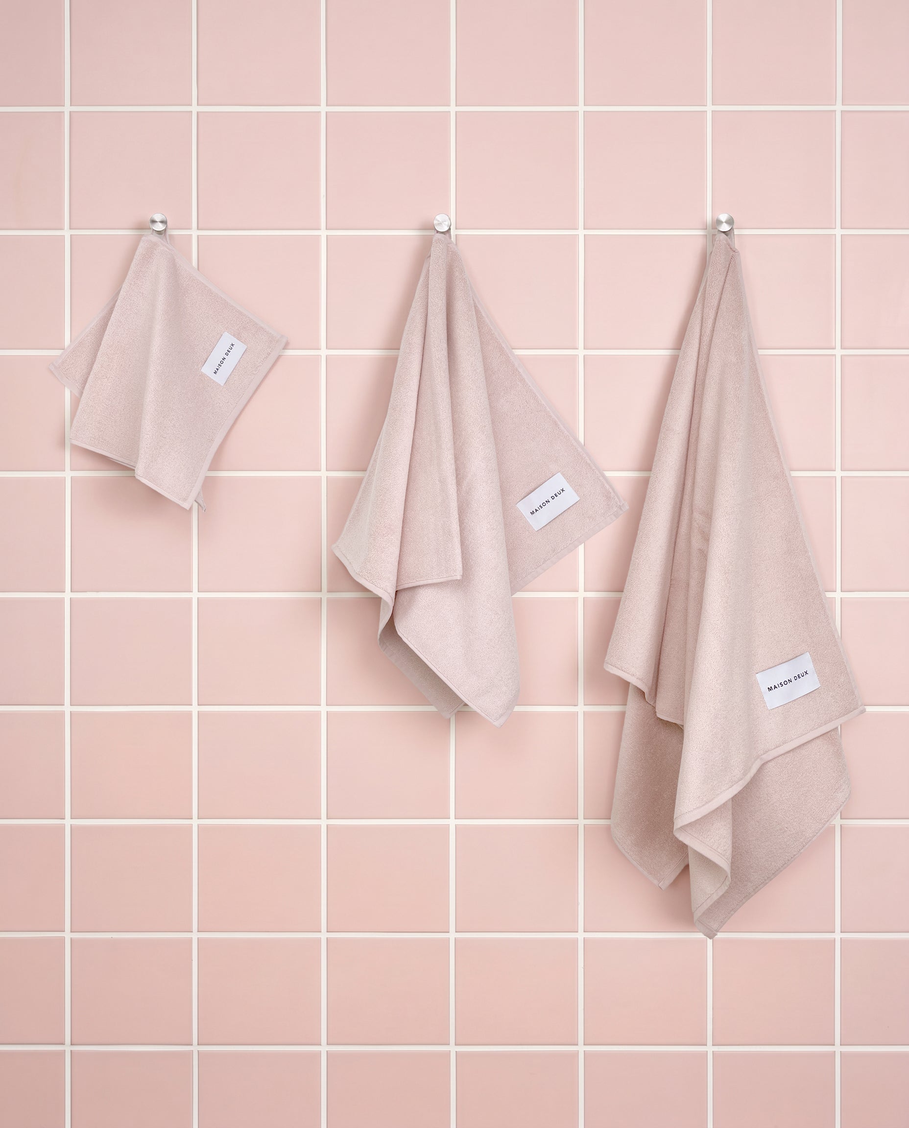 Solid pink organic cotton towels shown in guest, hand and bath sizes