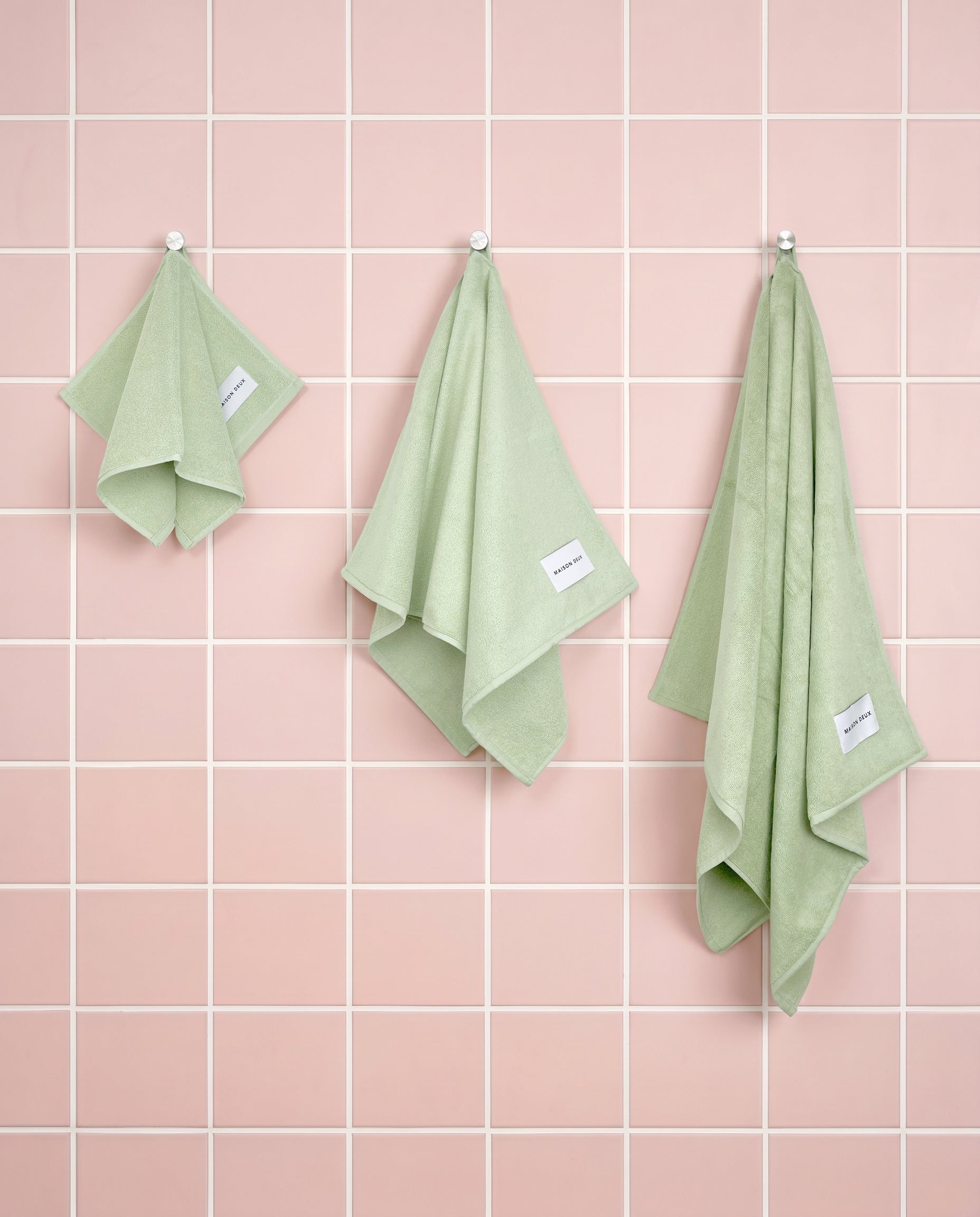 Solid sage green organic cotton towels shown in guest, hand and bath sizes