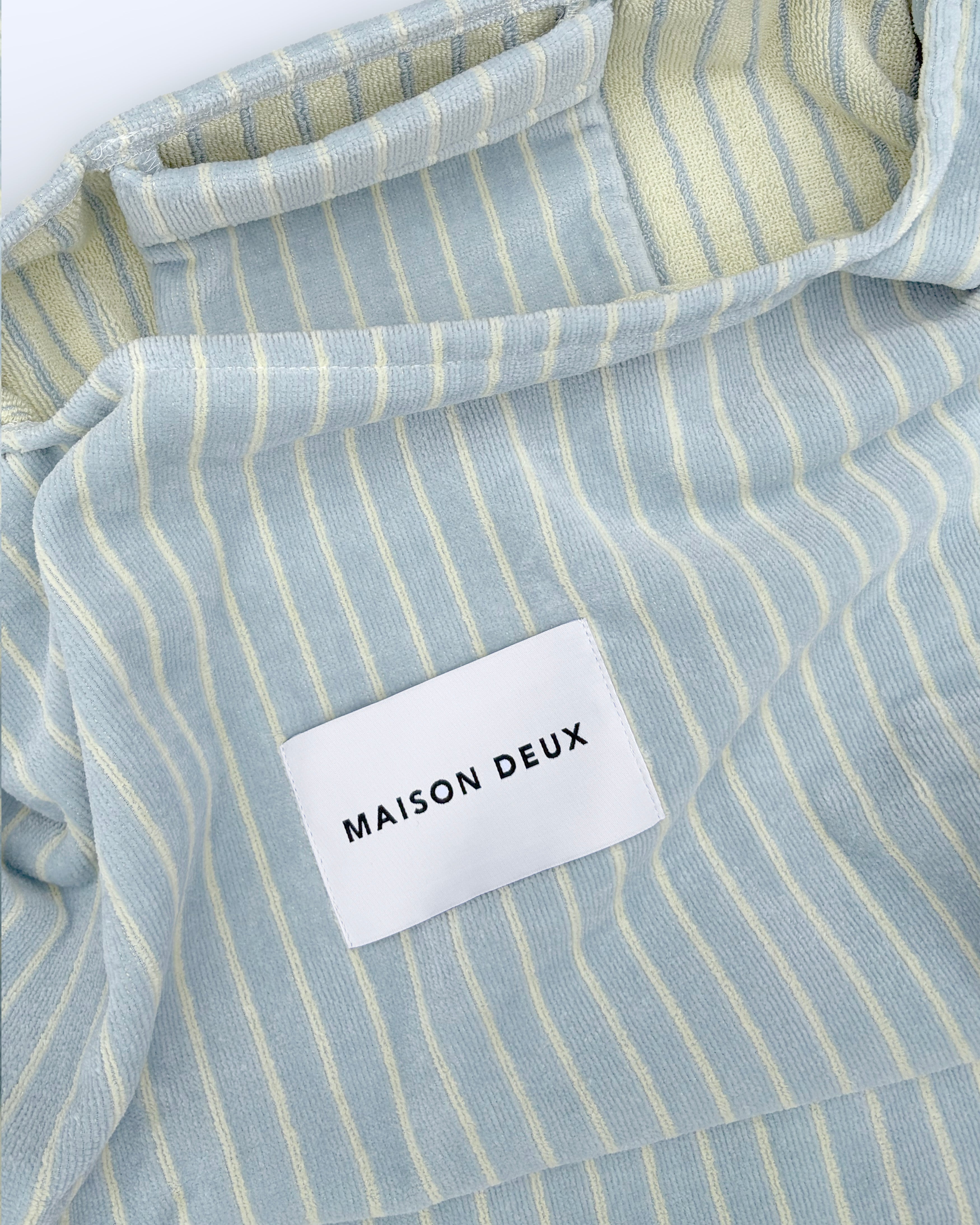 Close-up of blue and butter yellow striped terry bag fabric with woven label