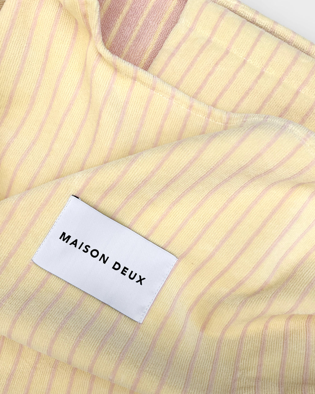 Close-up of butter yellow and pink striped terry bag fabric with woven label