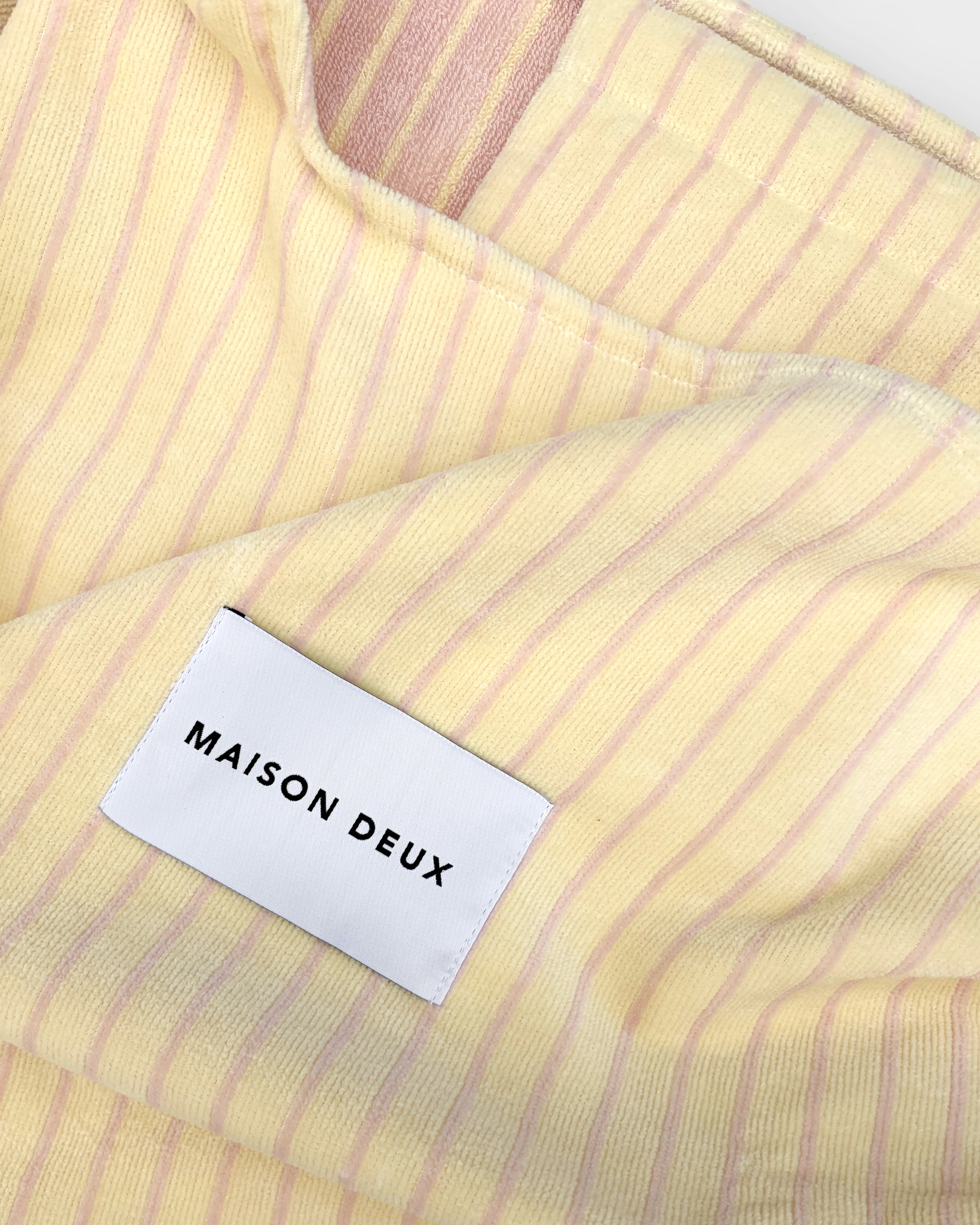 Close-up of butter yellow and pink striped terry bag fabric with woven label