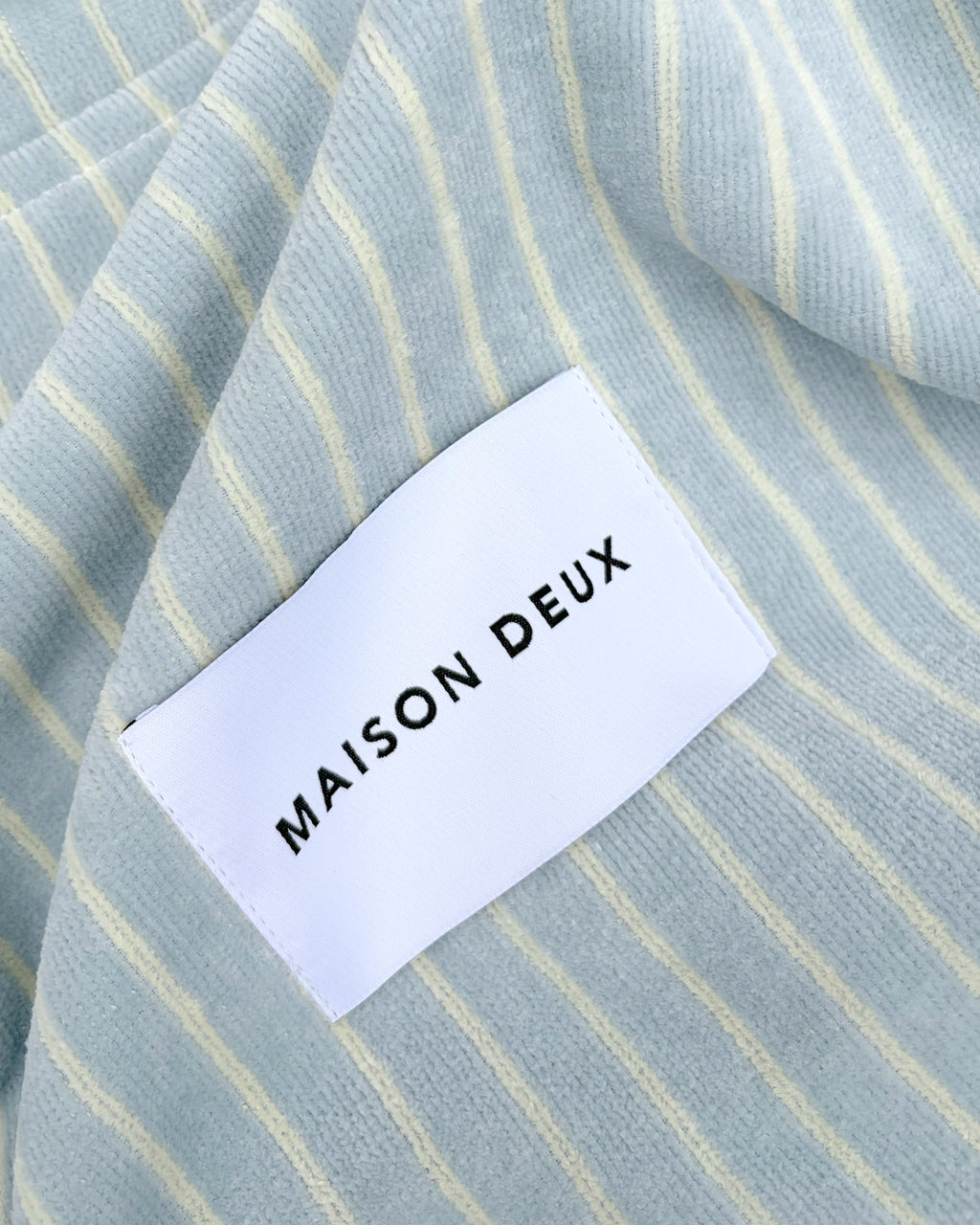 Close-up of blue and butter yellow striped terry fabric with woven label