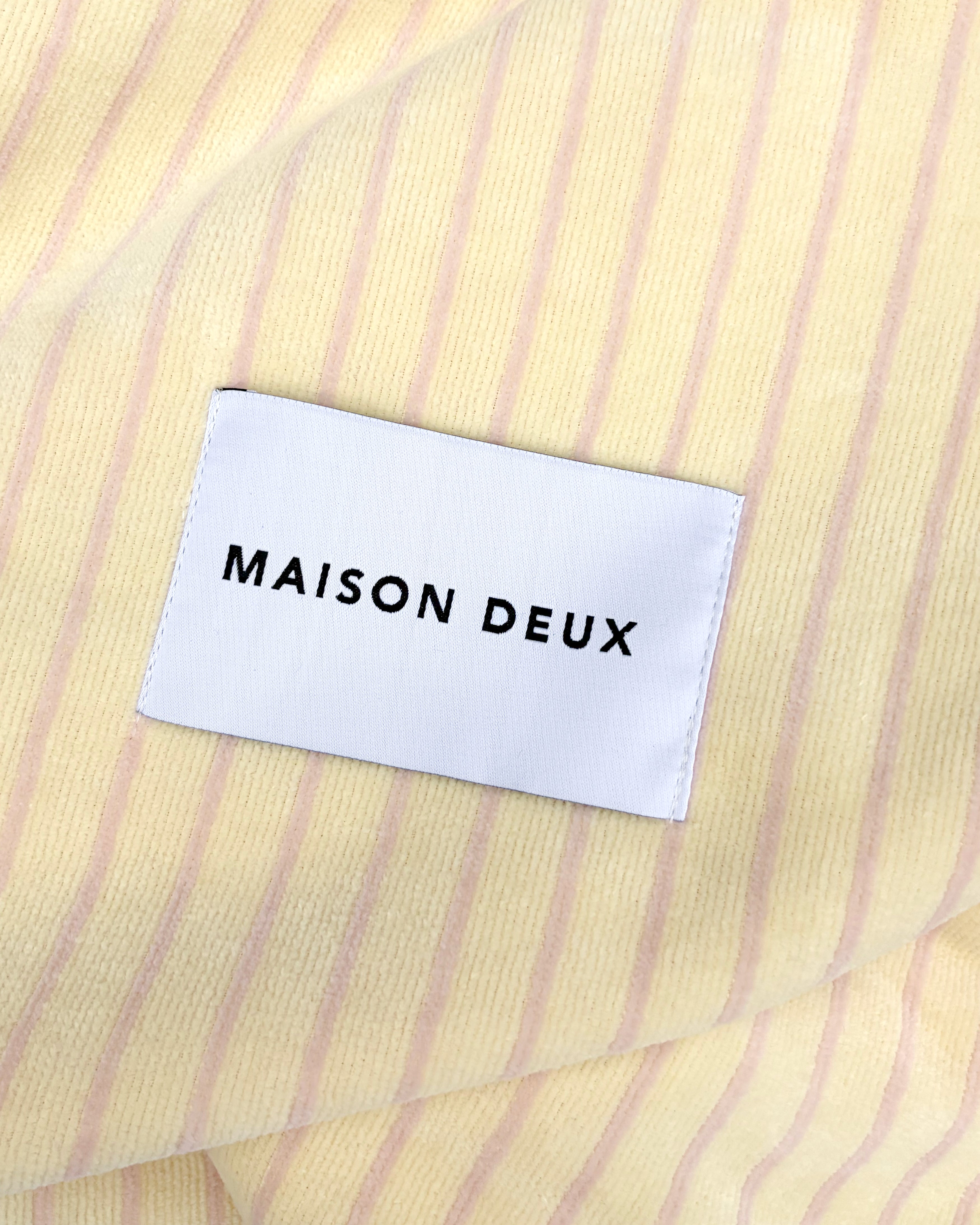 Close-up of butter yellow and pink striped terry fabric with woven label