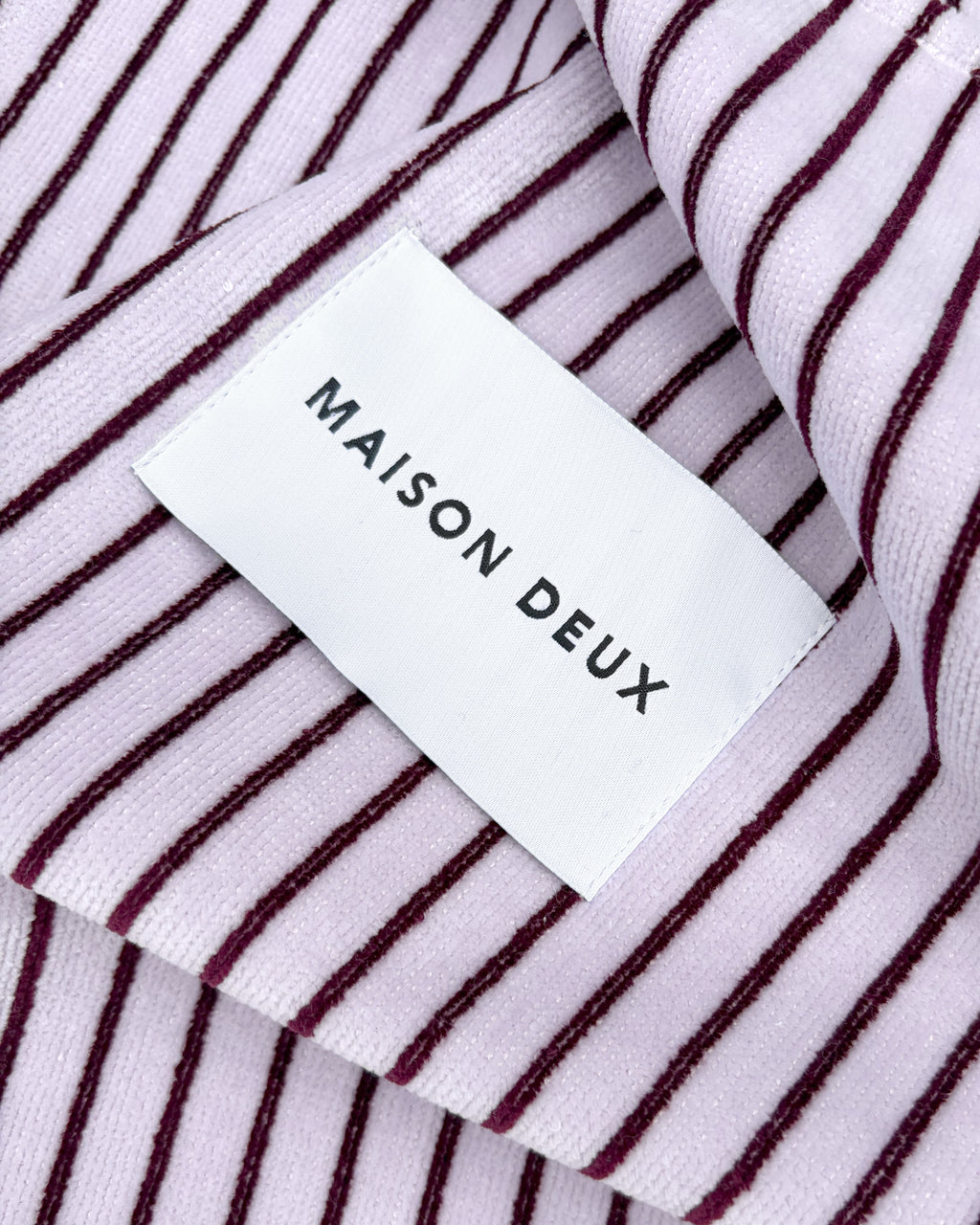 Close-up of lilac and bordo striped terry fabric with woven label