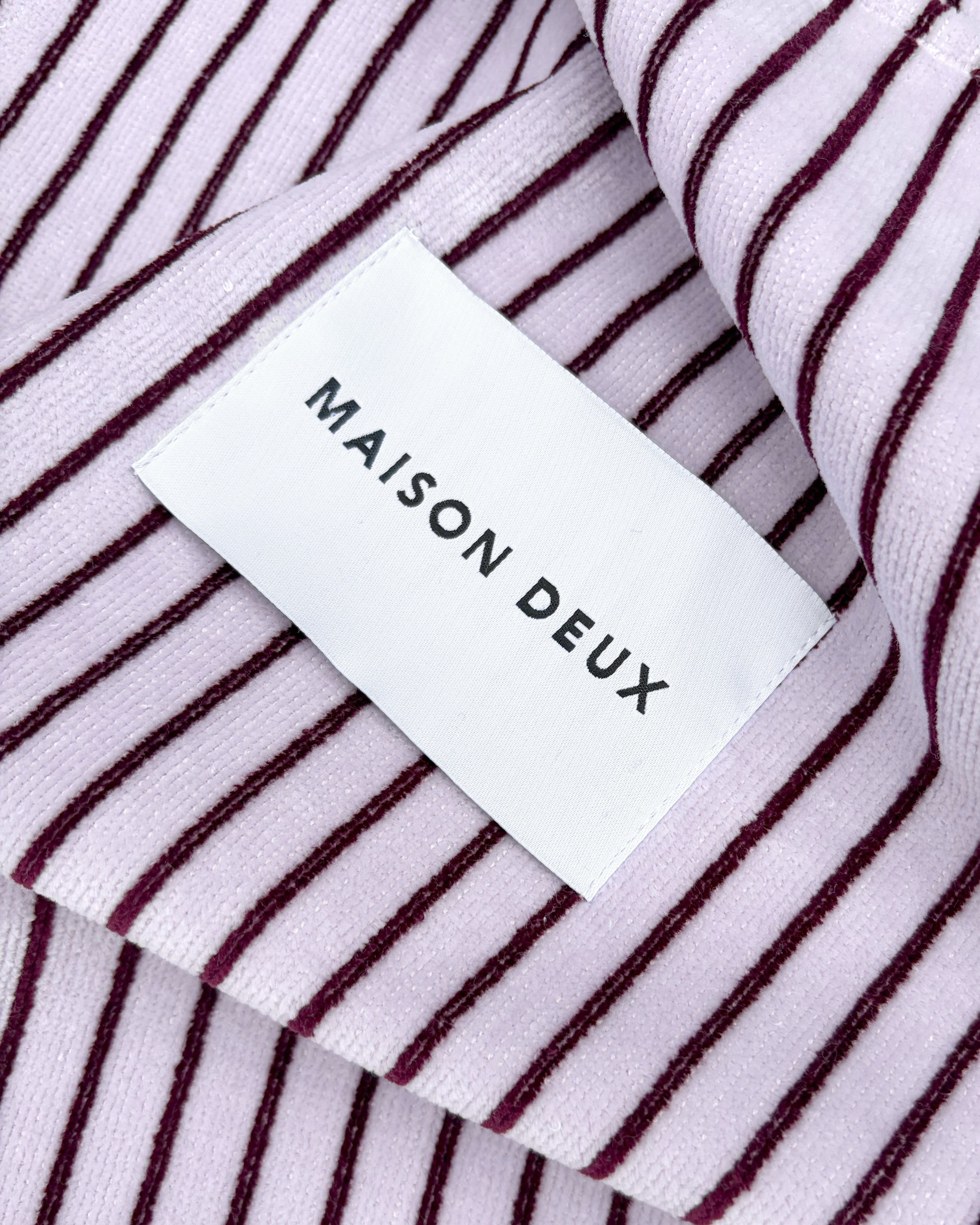 Close-up of lilac and bordo striped terry fabric with woven label