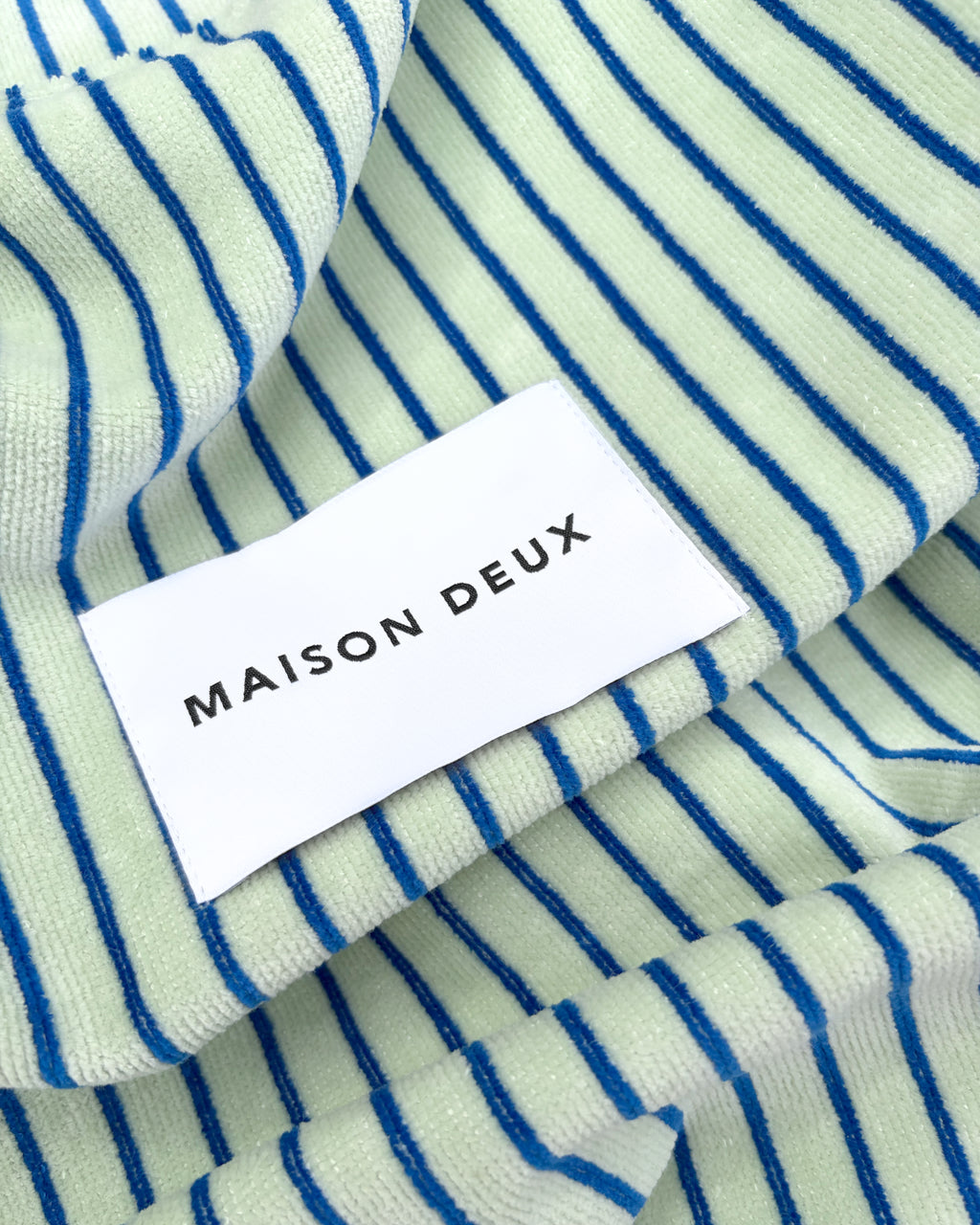 Close-up of sage and cobalt blue striped terry fabric with woven label
