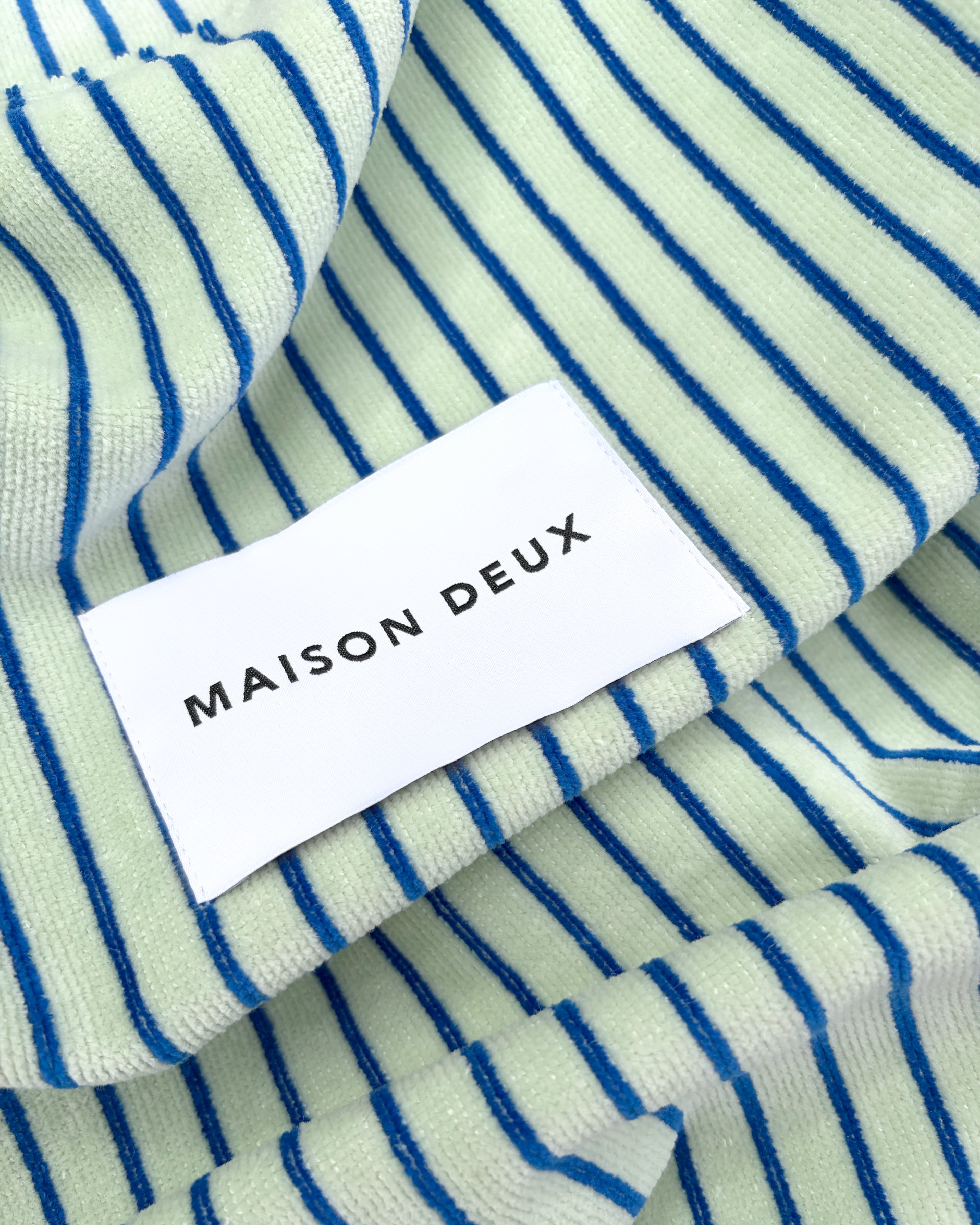 Close-up of sage and cobalt blue striped terry fabric with woven label