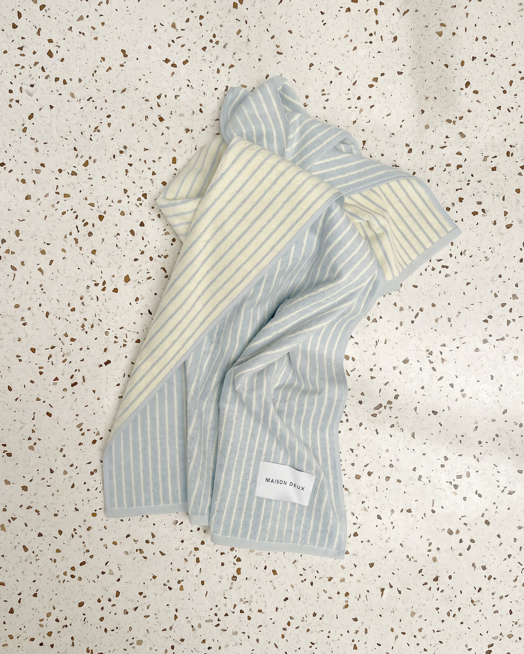 Folded blue and butter yellow striped towel on speckled countertop