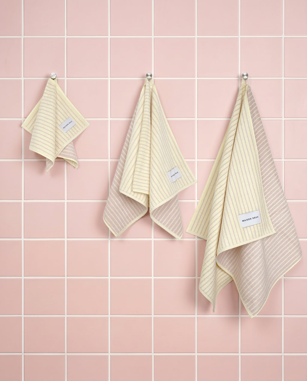 Butter yellow and pink striped organic cotton towels shown in guest, hand and bath sizes