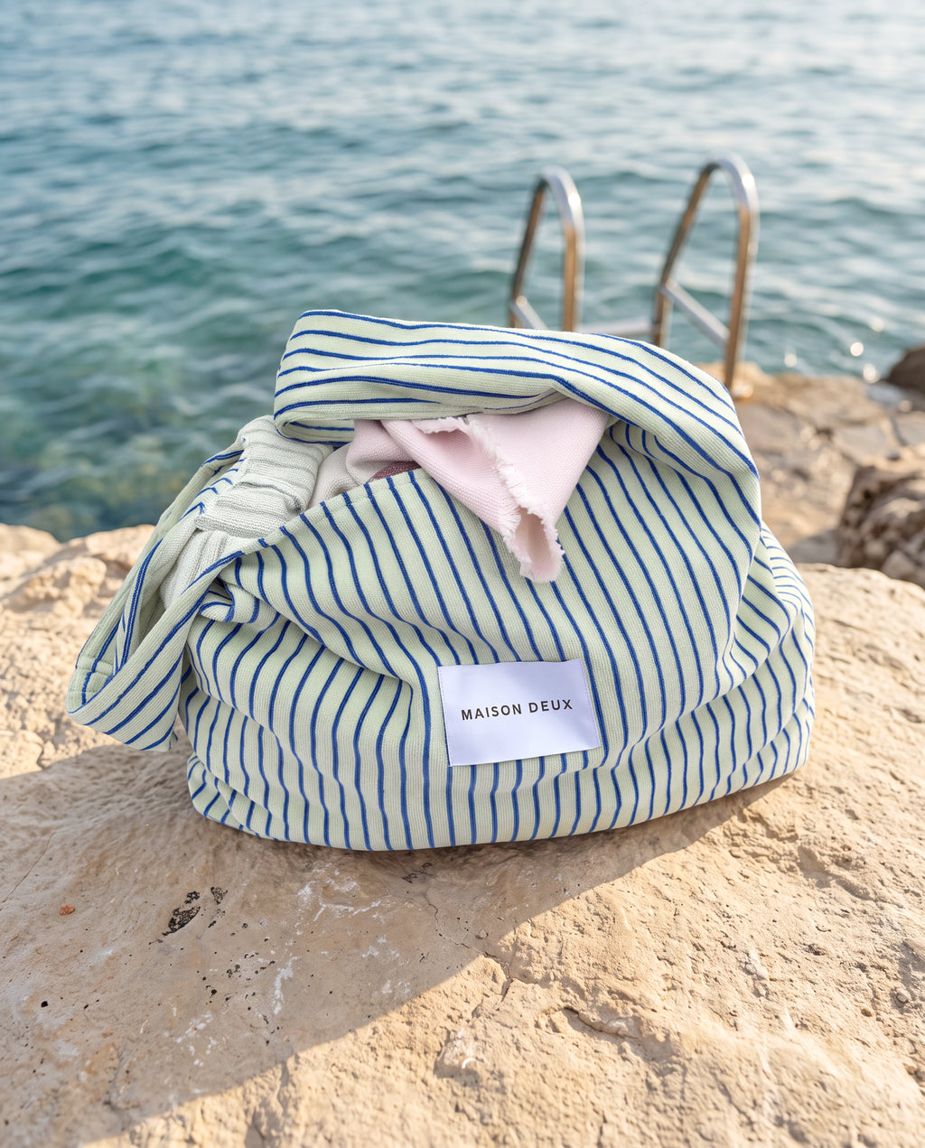 Sage and cobalt blue large terry beach bag styled on rocks by water